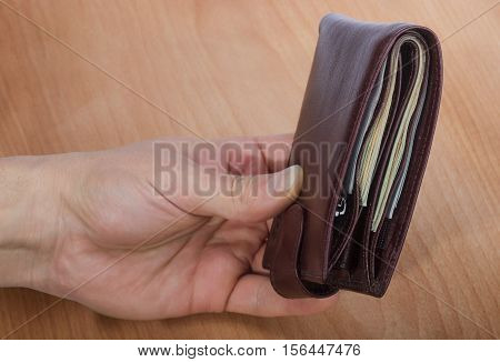 closed brown men's wallet with money in hand