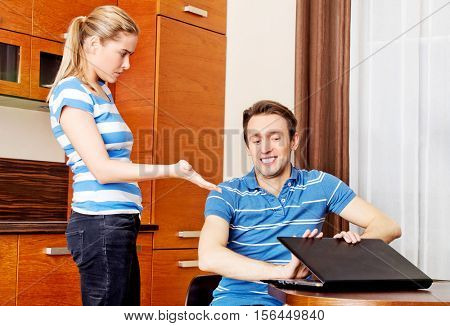 Man watching something on laptop, his wife is angry