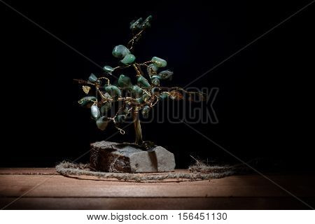 souvenir of a tree and colored green leaves of malachite stones isolated on darkbackground