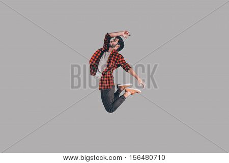 In mid-air. Mid-air shot of handsome young man jumping and gesturing against background