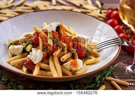 Vegetarian pasta garnished with tomato cheese and fresh herbs