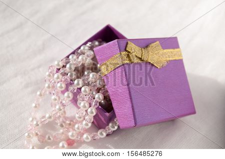 In an open box with a gold bow beautiful string of pearls