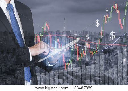 Businessman using digital tablet working with stock market chart in computer screen over the stock market exchange on tokyo cityscape in background Business trading and technology concept.