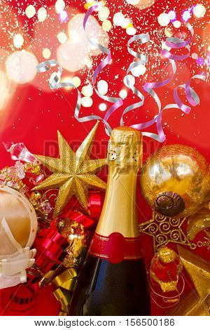 new year decorations with bottle of champagne on red background flat lay scene with with bokeh lights