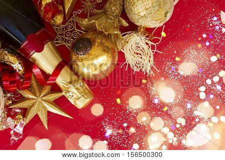 christmas decorations with bottle of champagne on red background flat lay scene with with bokeh lights