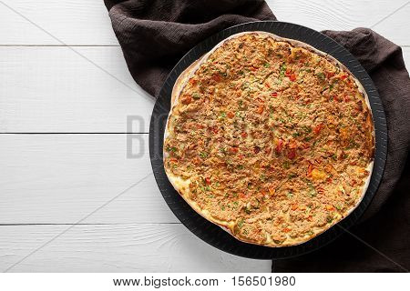 Lahmacun turkish homemade pizza with minced beef or lamb meat, paprika, tomatoes, cumin spice, parsley baked spicy middle eastern arabian food on white wooden table background