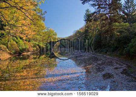 Arch Bridge in Kromlau, Saxony, Germany. Autumn in Park. Rakotz bridge in Kromlau