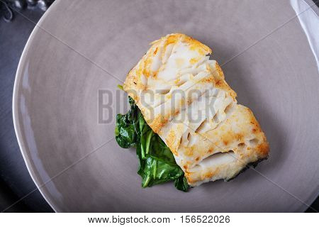 Fried cod fillets and spinach on a plate.