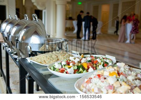 banquet table covered with salads and with people in the background