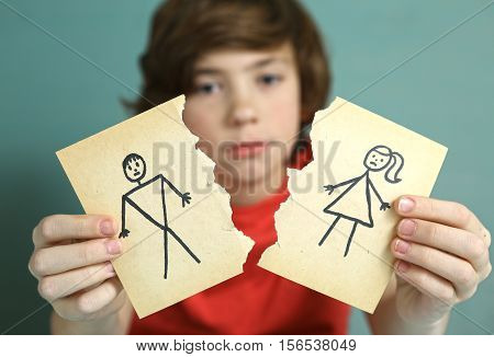 sad preteen boy unhappy about parents divorce hold man and woman paper drawing torn apart
