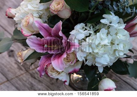 Wedding bouquet of white and pink flowers including roses, hydrangea, star gazer lilies and queen annes lace on a rustic table in the French countryside on Valentine's Day