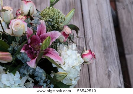 Wedding bouquet of white and pink flowers including roses, hydrangea, star gazer lilies and queen annes lace on a rustic table in the French countryside on Valentine's Day
