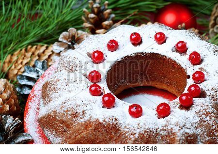Christmas table setting. Bundt cake pudding sprinkled with sugar powder decorated with red currant.