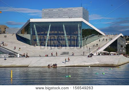 OSLO NORWAY - AUGUST 17 2016: Tourist on the Oslo Opera House which is home of Norwegian National Opera and Ballet and National Opera Theatre in Oslo Norway on August 172016.