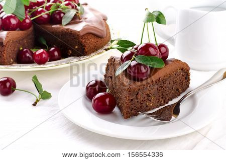 Chocolate cake with cherries and ganache cream on white background