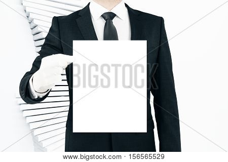 Businessman holding blank white poster on light baclground. Business concept. Mock up
