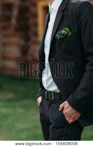 Unrecognizable man in suit standing outdoor. Close-up of groom with hands in pocket, waiting for bride.