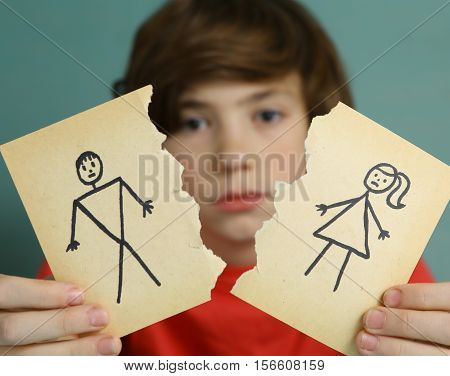 sad preteen boy unhappy about parents divorce hold man and woman paper drawing torn apart