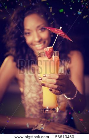 Young woman offering cocktail at bar counter against flying colours