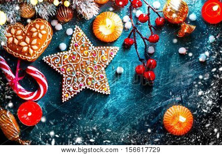 Christmas traditional food, Christmas Holiday Background with ornate Gingerbread cookies, Candy Cane and evergreens border over dark background table. Christmas and New year food. Christmas decoration