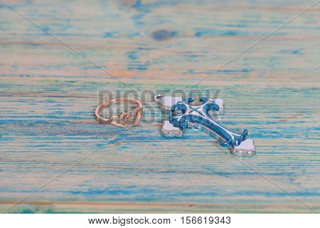 Wedding rings and coss on wooden table
