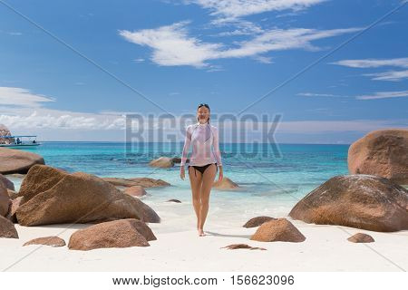 Woman wearing stylish bikini and lycra top enjoying swimming and snorkeling at amazing Anse Lazio beach on Praslin Island, Seychelles. Summer vacations on picture perfect tropical beach concept.