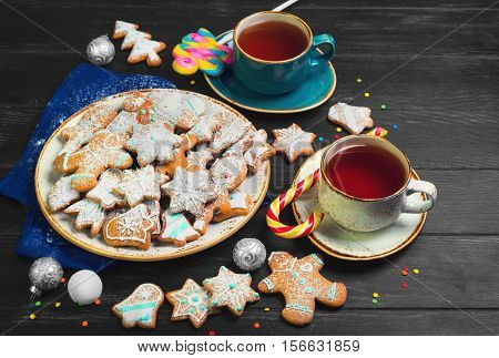 Christmas sweets baking gingerbread cookies on plate. Decorated for Christmas gingerbread cookies christmas bumps. Christmas cookies gingerbread on black table hot tea. New Year food.