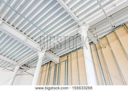Low angle view on structure girders with metal skeleton at indoor ceiling construction.