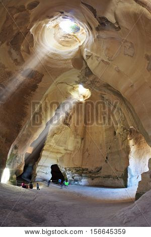 Israel National Park. Bell caves of Beit Guvrin. Picturesque clay arches illuminated by the sun from the hole at the top and side entrances