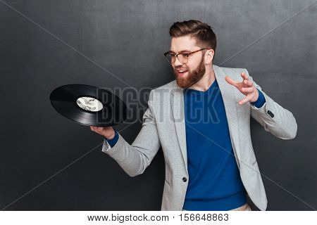 Hipster with vynil. in studio. laking at vynil. isolated black background