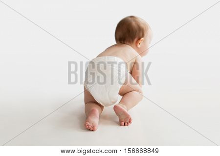 childhood, babyhood and people concept - little baby boy or girl in diaper crawling on white floor