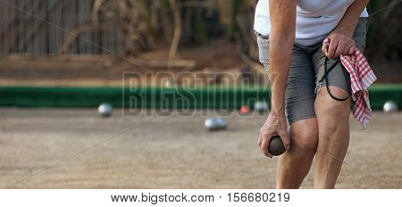 Senior playing petanque, balls on the ground