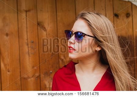 Happy blonde girl with red clothes and lips on a wooden background