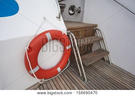 Safety equipment life buoy ring next to steps on teak deck of a luxury motor yacht