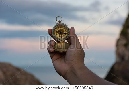 Compass in the hand on the nature background