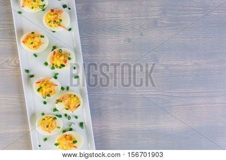 Deviled eggs garnished with green onions and bacon.