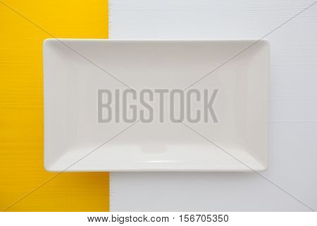 Empty white ceramic dish on over white and yelloe wooden table rectangle dish
