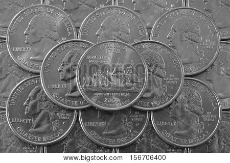 Coins of USA. Pile of the US quarter coins with George Washington and on the top a quarter of Virginia State.