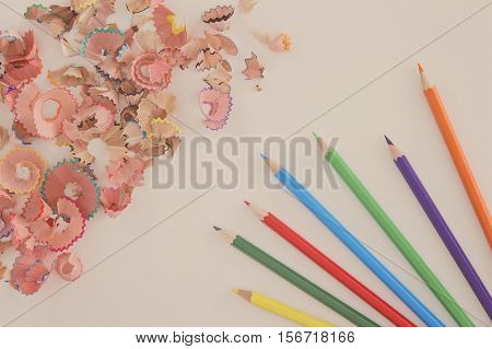 Multicolored pencils and shavings on white background with copy space. Top view. Toned image