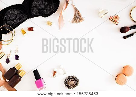 Flat lay for fashion and beauty blog and social media. Woman's glamour tools on a white background. Lace bralette jewelry perfumes spiral hair ties and hair clips nail polish mascara macaroons ribbon. Copy space for text. Horizontal