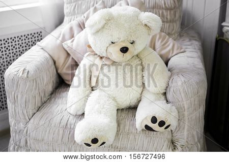 White Teddy bear. Room with white soft toy. Interior of the room in soft and light colours.