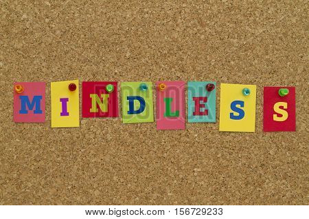 Mindless word written on colorful sticky notes pinned on cork board.