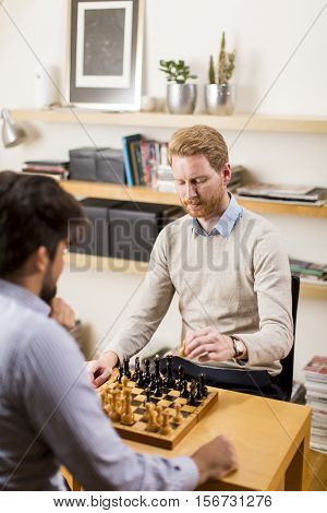 Two young men playing chess in room