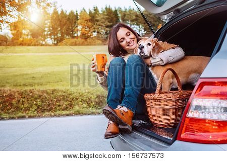 Woman with her dog have a tea time during their autumn auto travel