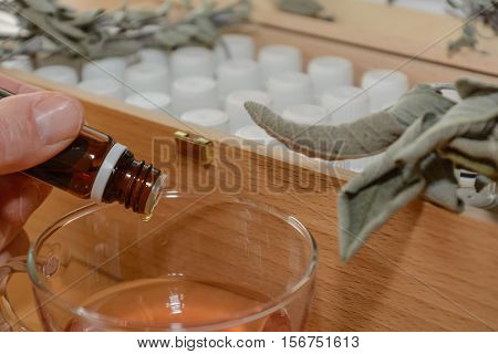 From a brown remedy person drops liquid into juice - close-up