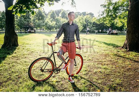 Hipster with red bycicle and tattoo on leg in park