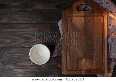 cup with brown wooden cutting board on a brown table top