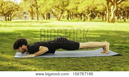 Hispanic man practicing doing yoga in the park on the grass. Lifestyle.