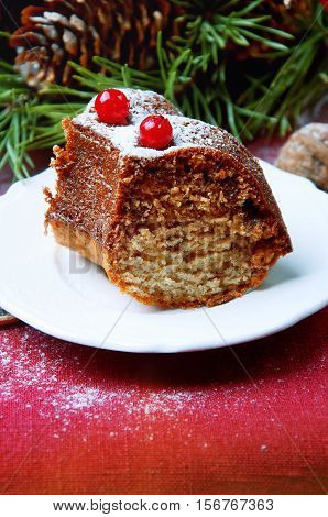 Piece of christmas pudding cake on white saucer decorated with berries sprinkled with sugar powder. Traditional christmal food.