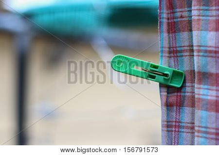 Plastic clothespin green pin and chintz drying on washing line